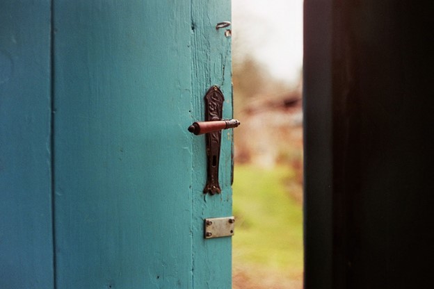 a green door is ajar showing the outside, open for opportunities